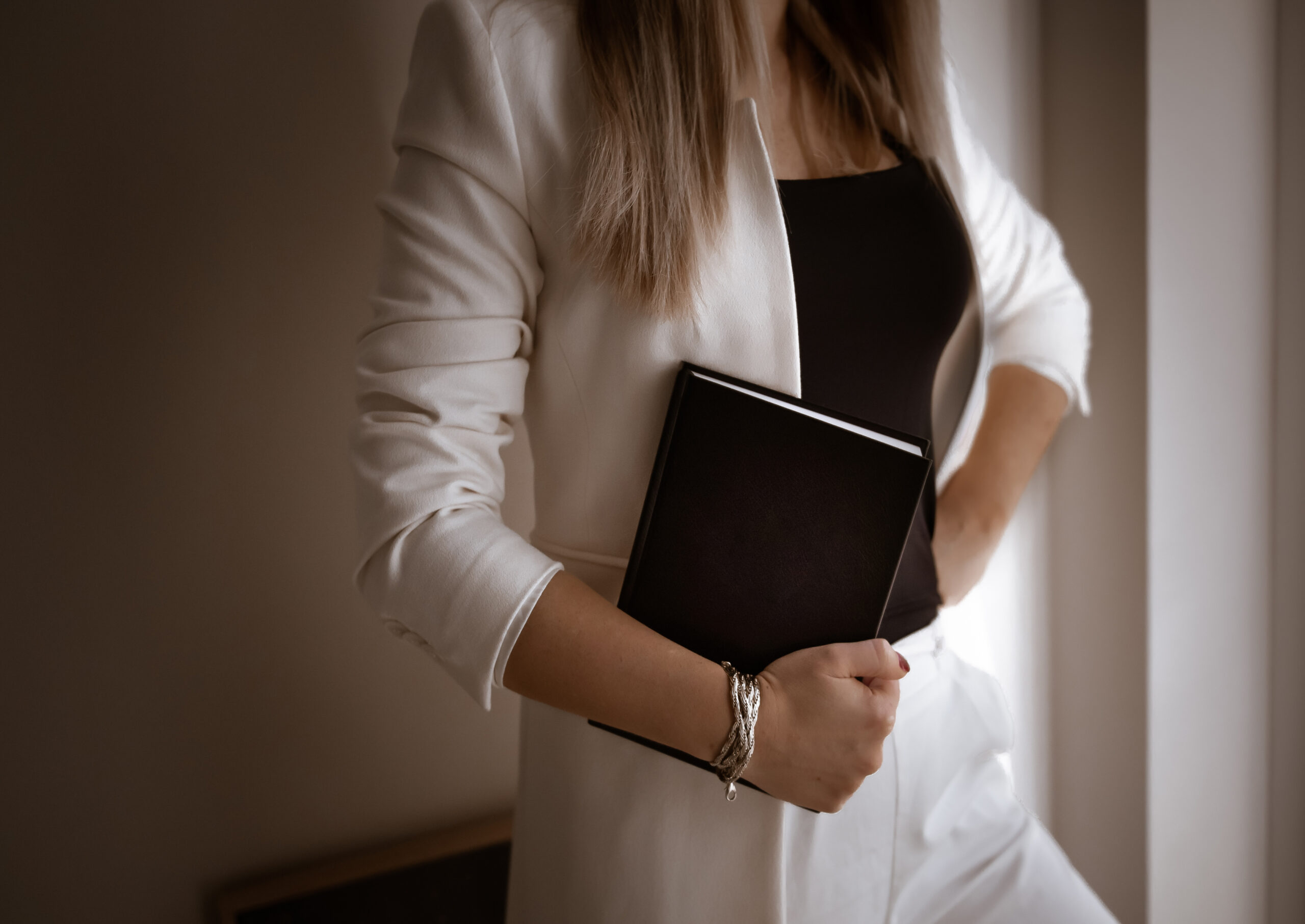 Woman in a white suit holding a book